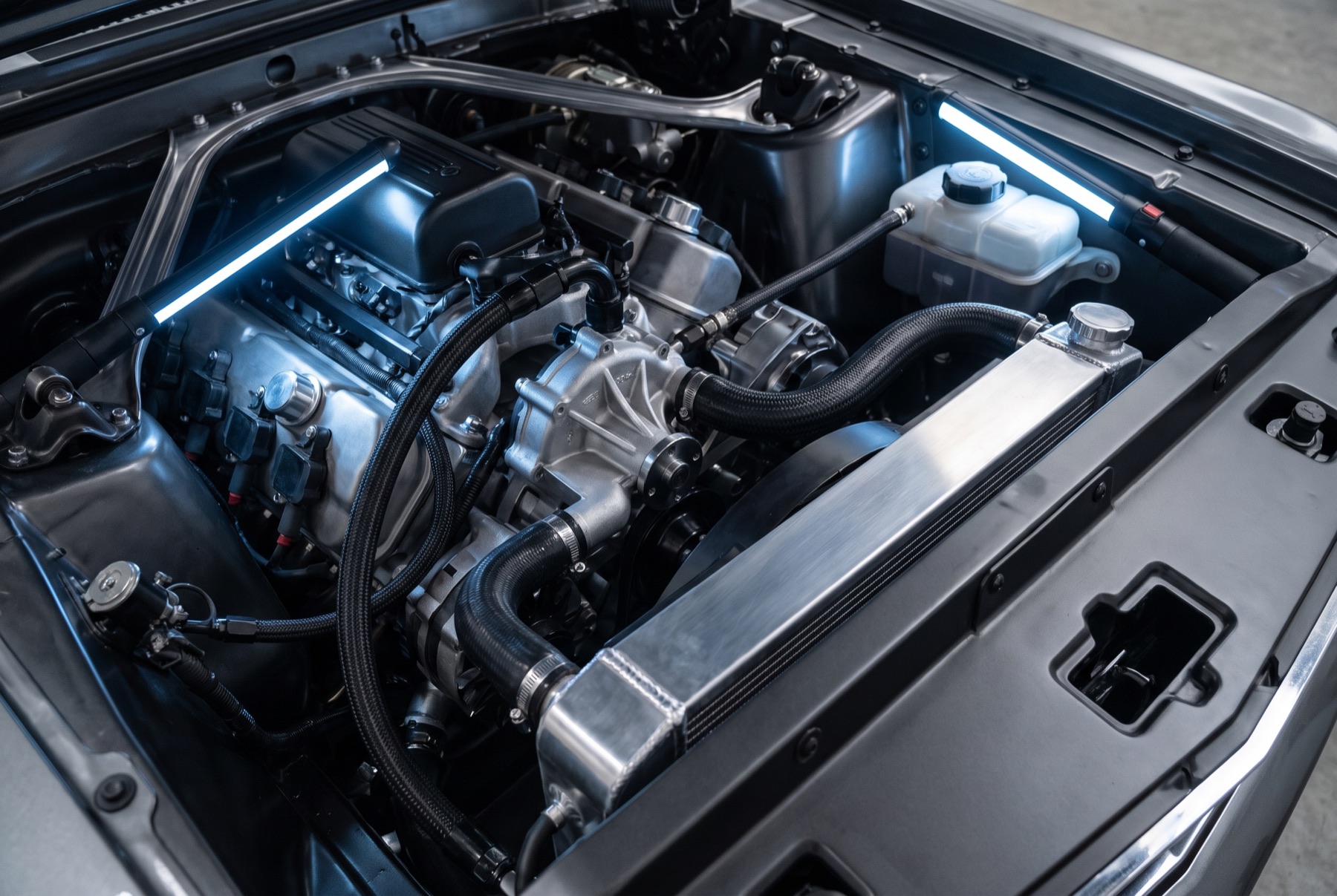 Engine bay showing cooling system components lit in cool blue-white light