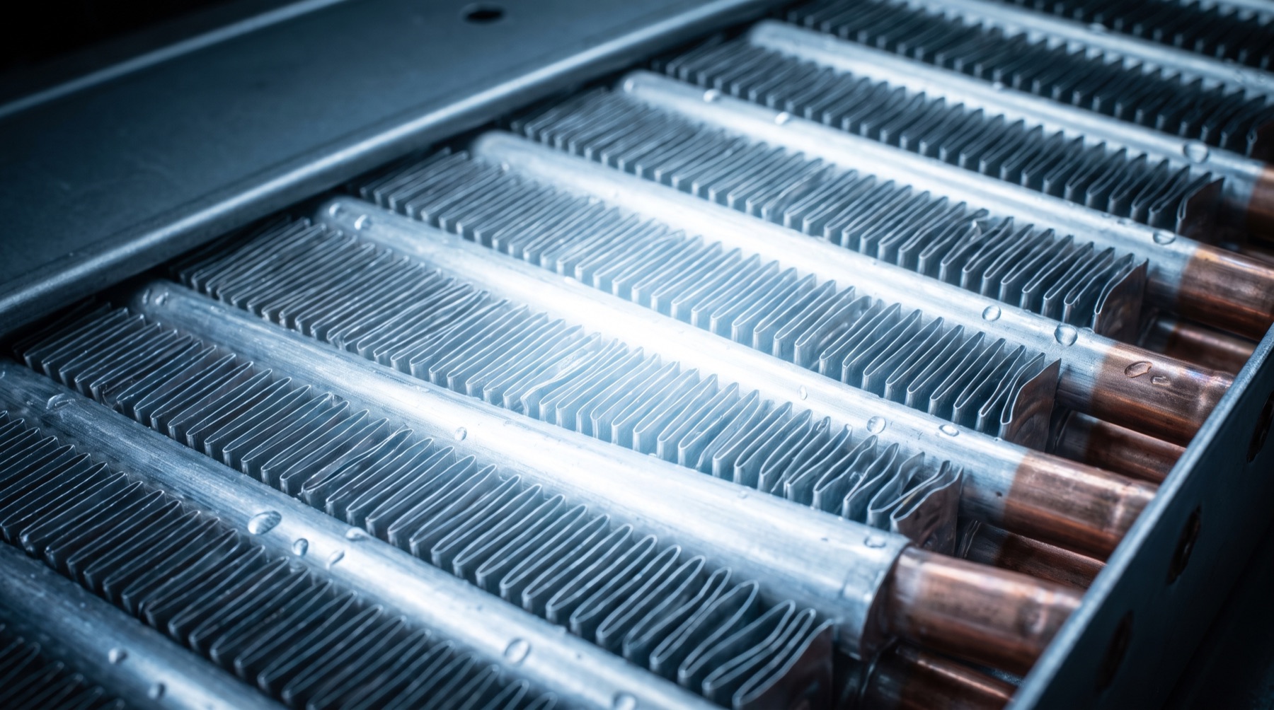 Macro detail of a radiator core lit in cool blue-white light, showing rows of aluminum cooling fins