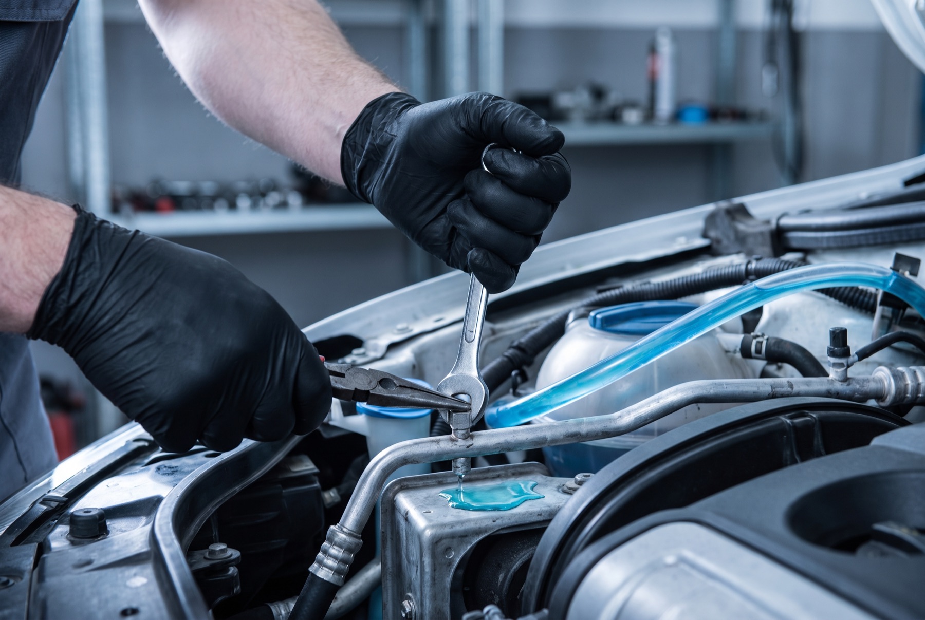 Technician's hands servicing a car's coolant system with precision tools